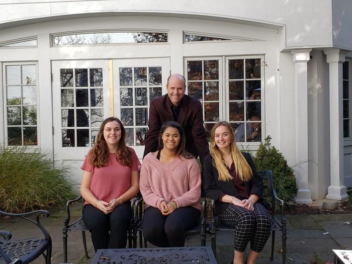 Three students and Paul Perreault in front of the Nittany Lion Inn